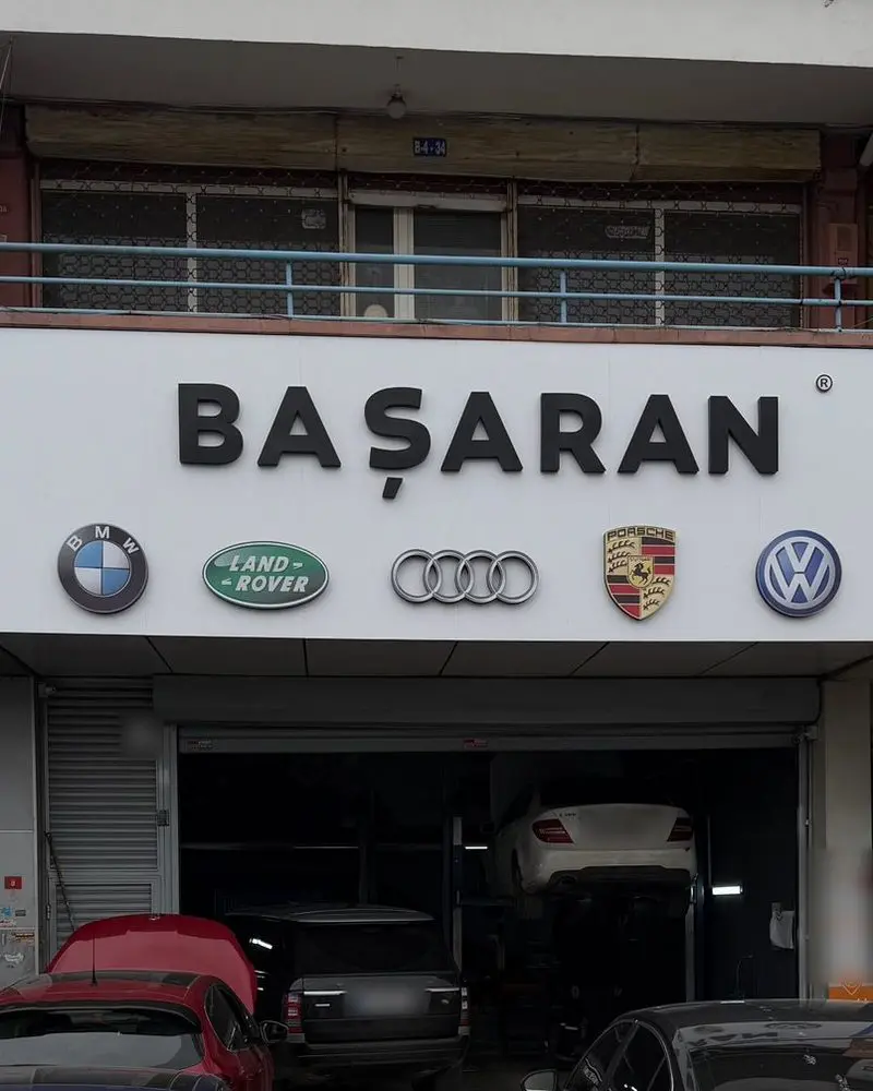 Başaran Servis'in Kartal Oto Sanayi Sitesi'ndeki dükkân cephesi: üzerinde hizmet verilen markaların amblemleri bulunan tabela ve servisteki araçlar